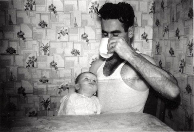 Vintage photo of a man holding a baby drinking coffee