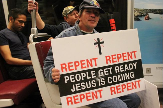Man carrying a sign asking people to repent because Jesus is coming